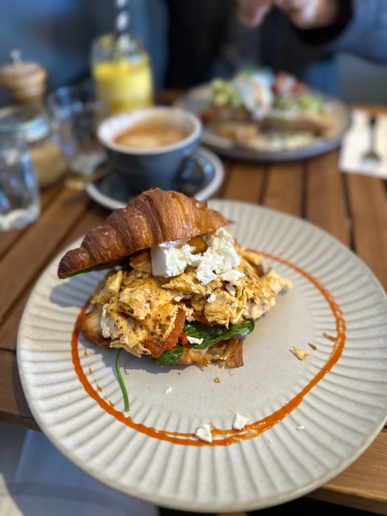 A popular brunch dish of smashed avocado on toast with poached egg, lemon, basil and hummus at Birdcage Café Altona