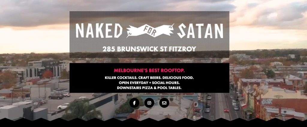 Rooftop view at Naked for Satan in Fitzroy featuring city skyline, outdoor seating, and colourful cocktails on the table