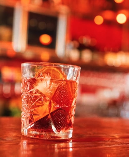 Rooftop view at Naked for Satan in Fitzroy featuring city skyline, outdoor seating, and colourful cocktails on the table