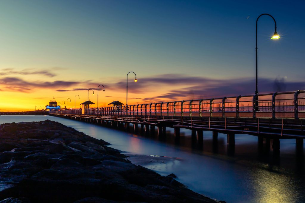 Captivating sunset view of St Kilda Pier in Melbourne with dramatic skies and tranquil water.