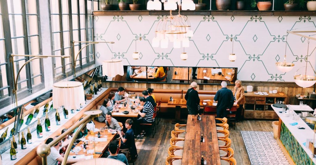 Spacious restaurant with stylish interior design, featuring wooden tables and a group of diners enjoying a meal.