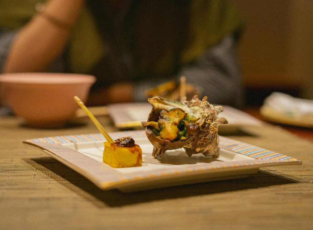 Exquisite seafood dish with shellfish and sauce, served in a Japanese setting. Perfect for gourmet dining experiences.