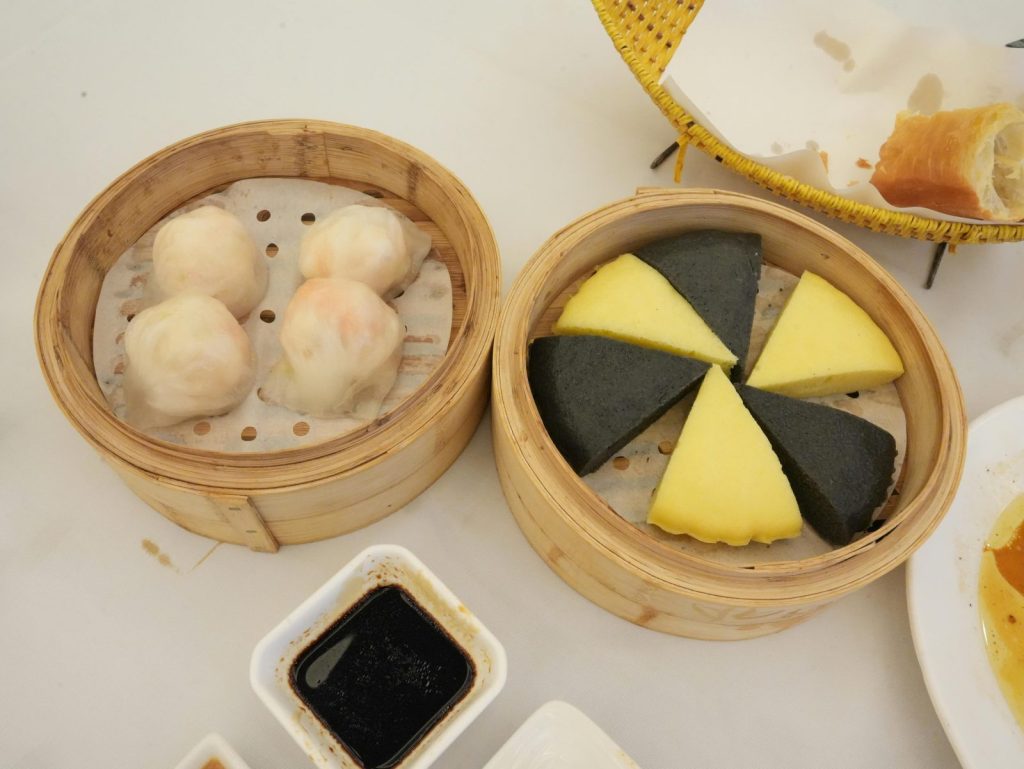 Top view of assorted dim sum, including dumplings and steamed cakes, served with soy sauce.