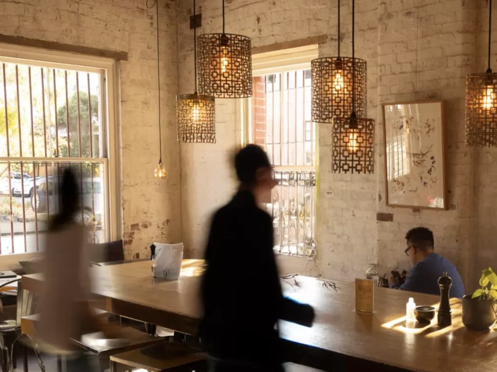 A busy Melbourne café during brunch service, with diners enjoying coffee and plates of food in a bright, modern space